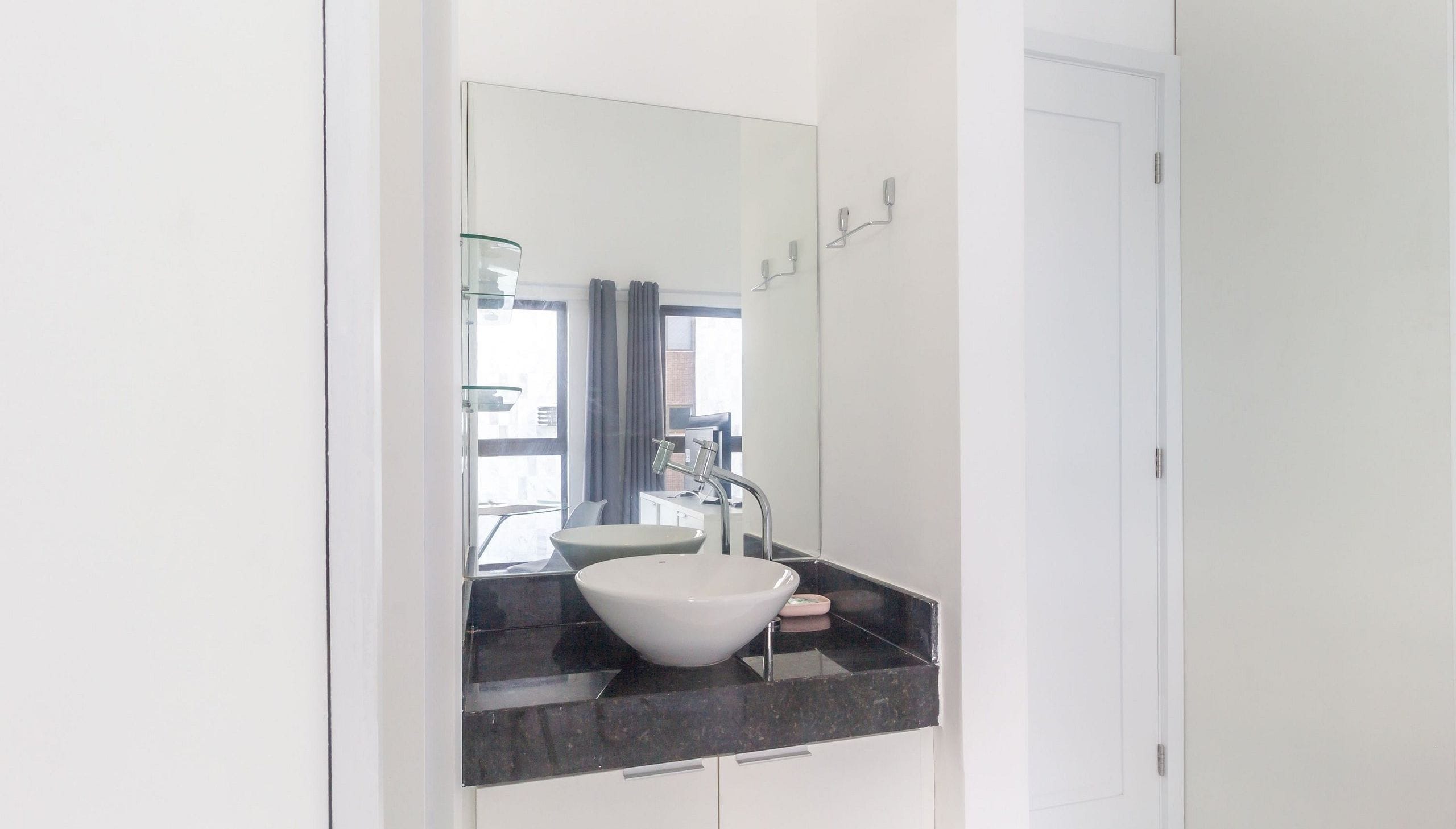 A modern bathroom with a white sink, dark countertop, and a large mirror.