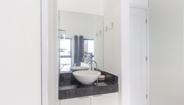 A modern bathroom with a white sink, dark countertop, and a large mirror. - Luxury Beachfront Apt in Boa Viagem - Iaa1003 (Recife)