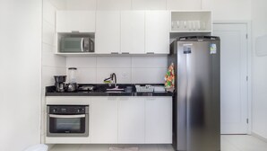 A modern kitchen with white cabinets, a stainless steel refrigerator, a coffee maker, and a microwave. - Comfortable Seaside Apt in Boa Viagem Iaa0502 (Recife)