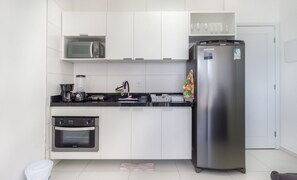 Eine moderne Küche mit weißen Schränken, einem Edelstahlkühlschrank, einer Kaffeemaschine und einer Mikrowelle.