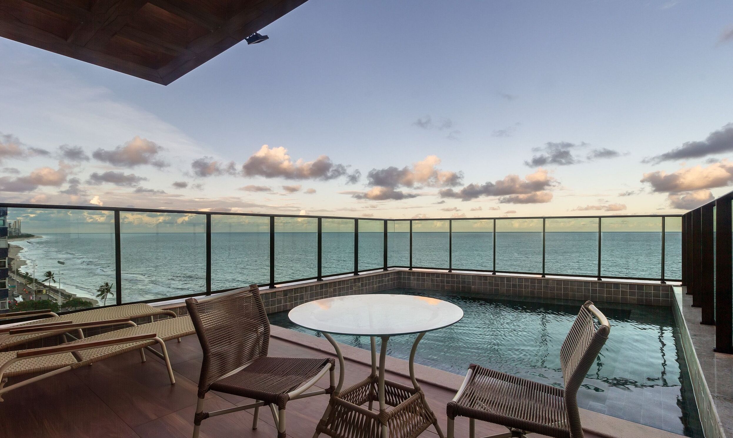 A balcony with a glass railing, a pool table, and wicker chairs.