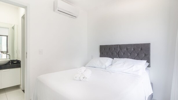 A hotel room with a bed, a bathroom with a sink, and an air conditioning unit. - Studio w/ sea View in Bldg w/ gym - Iaa0503 (Recife)