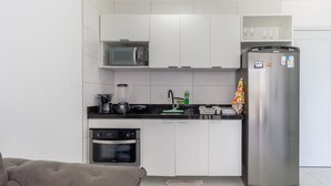 A modern kitchen with white cabinets, a built-in microwave, a refrigerator, a coffee maker, and a toaster. - Studio w/ sea View in Bldg w/ gym - Iaa0503 (Recife)
