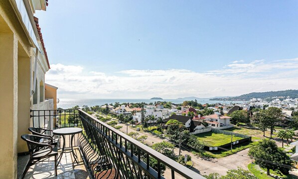 Uma varanda com vista para uma cidade costeira, incluindo casas e uma praia.