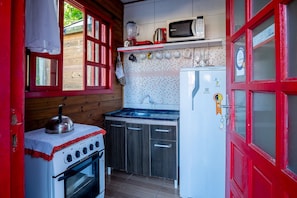 A compact kitchen with a stove, oven, microwave, and refrigerator. - Charming Cabin 11 Minutes From Rosa Beach Prj001 (Imbituba)