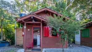 Una cabana de fusta amb un porxo, una cuina petita i una porta vermella.