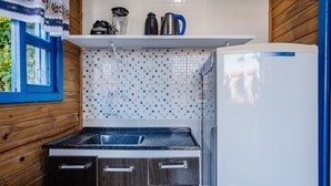 Una cocina compacta con estufa negra, refrigerador blanco y salpicadero de azulejos.