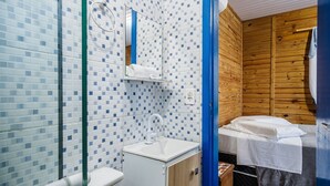 Un baño pequeño y funcional con un lavamanos blanco, un espejo y una zona de ducha.