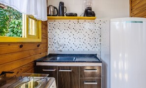 Uma cozinha compacta com bancada de madeira, pia e geladeira.