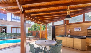An outdoor patio area with a pool, wooden pergola, and a bar area with seating. - Cozy Apartment 200m From the Beach, Marau Cpr0107 (Maraú)