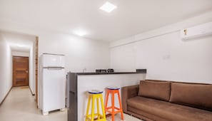 A compact living space with a kitchenette, a brown sofa, and two colorful stools. - Cozy Apartment 200m From the Beach, Marau Cpr0107 (Maraú)