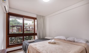 A hotel room with a bed, a window with curtains, a ceiling fan, and an air conditioning unit. - Cozy Apartment 200m From the Beach, Marau Cpr0107 (Maraú)