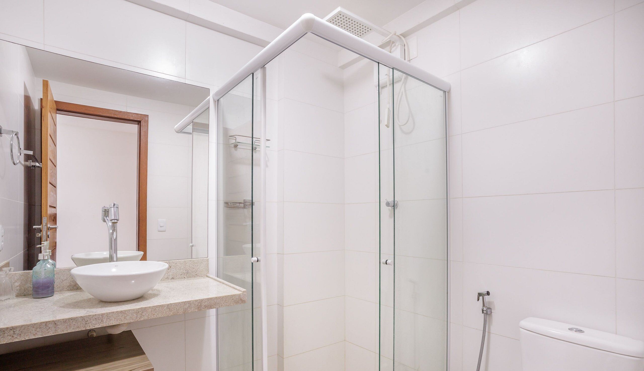 Un baño moderno con ducha de vidrio, lavamanos blanco y espejo.