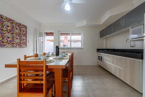 Eine moderne Küche mit Holzschränken, einer schwarzen Arbeitsplatte und einem Essbereich mit Holztisch und -stühlen.