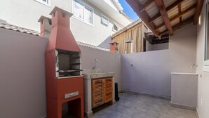 An outdoor kitchen area with a built-in grill, a sink, and a wooden cabinet. - House in Condo With Pool Near the Beach Mgi025 (Porto Seguro)