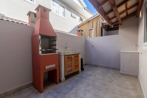 Ein Außenbereich mit Küche, inklusive integriertem Grill, Spüle und Holzschrank.