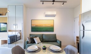 Una sala moderna con un sofá, una mesa de comedor para dos personas y un cuadro grande en la pared.
