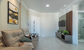 Una sala de estar moderna con un sofá color beige, un televisor montado y un diseño minimalista.