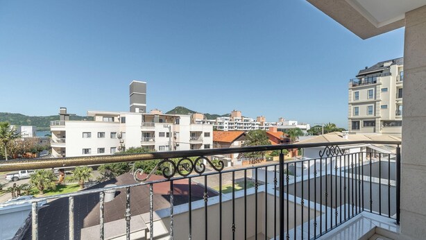En bostadsbyggnad med flera balkonger, en klar himmel och ett kuperat landskap i bakgrunden.