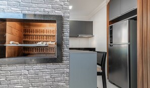 Una cocina con pared de ladrillo, una parrilla empotrada, un refrigerador de acero inoxidable y muebles de cocina modernos.