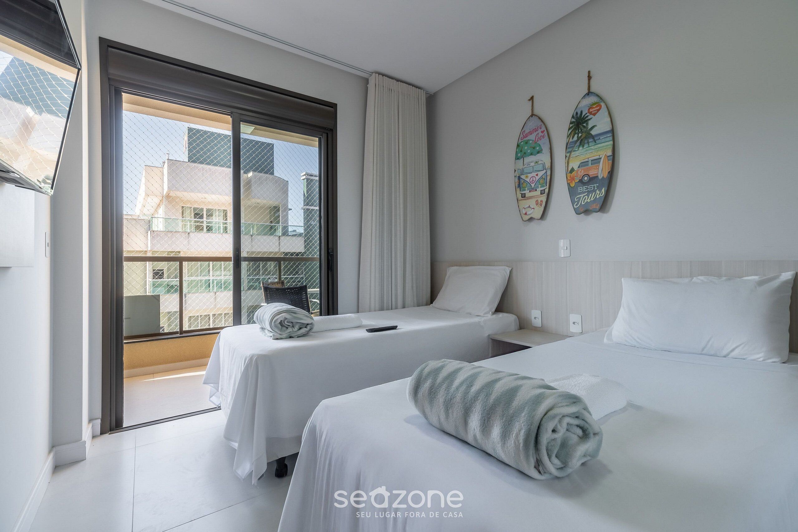 A hotel room with two beds, a large window, and a view of buildings outside.