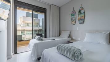 Habitación de hotel con dos camas, un ventanal grande y vistas a edificios.