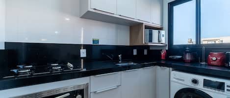 A modern kitchen with a built-in oven, a washing machine, and a large window.