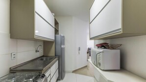 A narrow kitchen with white cabinets, a gas stove, a refrigerator, and a microwave. - 2-bedro ap in Cond W/pool, 850 m the Beach Vgt0004 (Ilhéus)