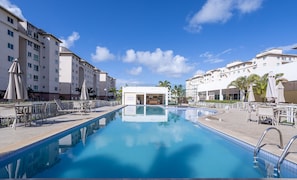A swimming pool with lounge chairs and umbrellas, surrounded by multi-story buildings with balconies. - 2-bedro ap in Cond W/pool, 850 m the Beach Vgt0004 (Ilhéus)