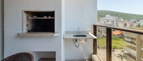A balcony with a tiled wall, a small window, and a metal sink.