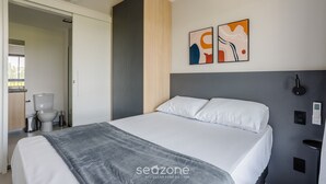 A modern hotel room with a bed, a bedside table, a wall-mounted light, and a painting. - Charming Modern Apartment in Santo Amaro Noa0704 (São Paulo)