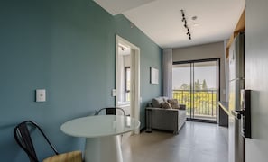 A modern living room with a glass table, a sofa, and a balcony with a view. - Charming Modern Apartment in Santo Amaro Noa0704 (São Paulo)