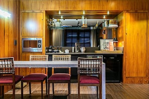 A wooden-paneled kitchen with a central island, bar stools, and a built-in oven. - Renovated Penthouse in a Luxury Resort Ilc3503 (Florianópolis)
