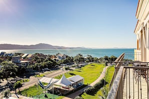 A coastal hotel with a view of the sea and mountains, a parking area, and a grassy lawn. - Renovated Penthouse in a Luxury Resort Ilc3503 (Florianópolis)