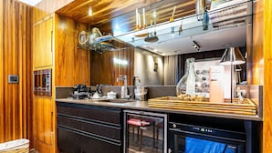 Cozinha moderna com painéis de madeira, máquina de lavar louça embutida e frigorífico com porta de vidro.