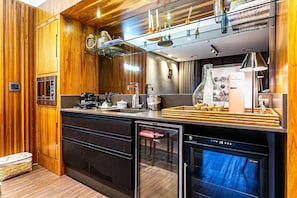 A modern kitchen with wooden paneling, a built-in dishwasher, and a glass-fronted refrigerator. - Renovated Penthouse in a Luxury Resort Ilc3503 (Florianópolis)