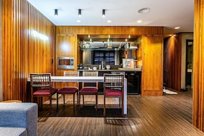 Une cuisine moderne avec un lambris en bois, un îlot central et un coin repas doté de chaises à revêtement rouge.