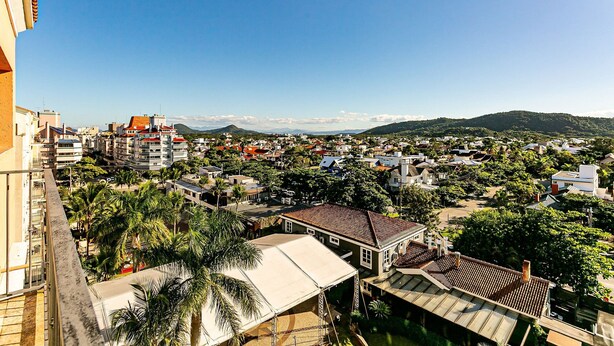Bairro residencial com casas, palmeiras e uma montanha ao fundo.