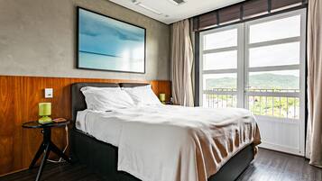Quarto de hotel com uma cama grande, vista para o exterior e um quadro na parede.