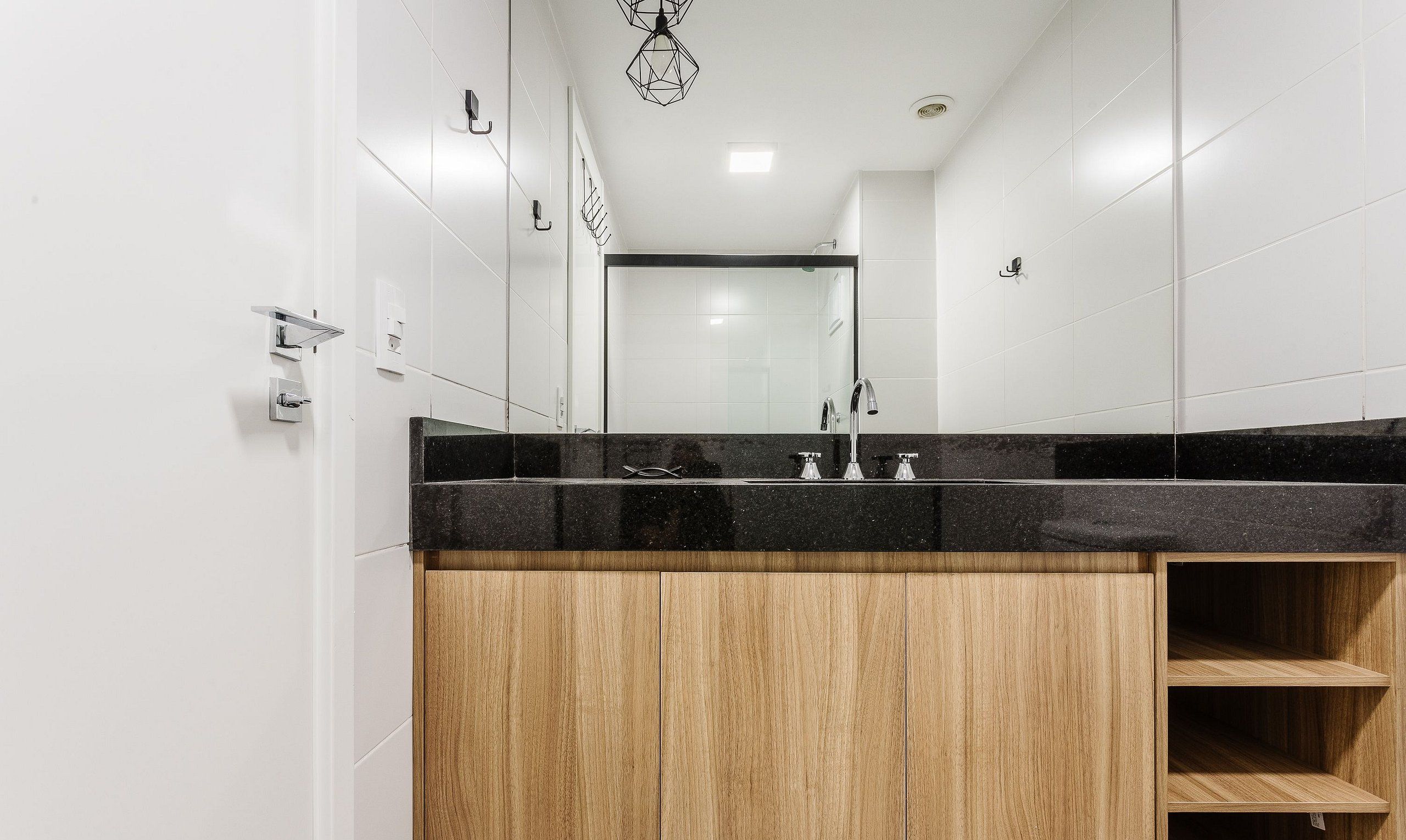 A modern bathroom with a black countertop, wooden cabinets, and a large mirror.