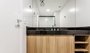 Une salle de bain moderne avec un plan de toilette noir, des meubles en bois et un grand miroir.