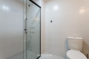 A bathroom with white tiles, a glass shower enclosure, and a white toilet. - Modern Studio Near USP - Hmo0410 (São Paulo)