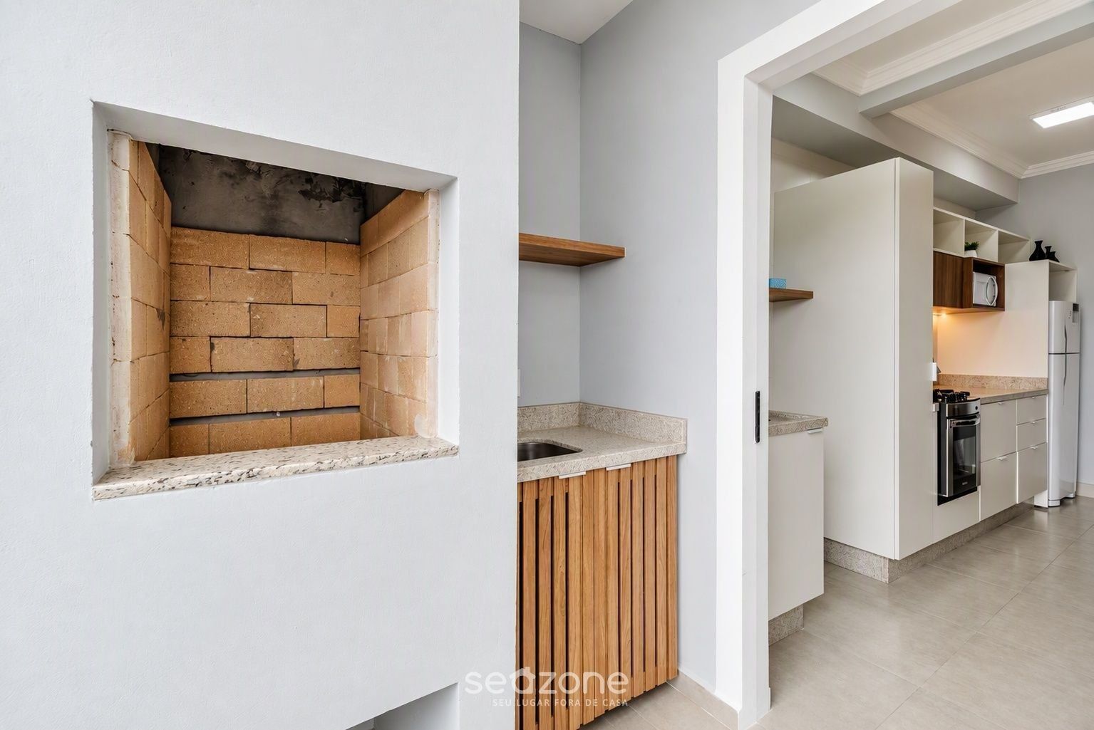Una cocina moderna con horno de ladrillo integrado, armarios blancos y encimera de madera.