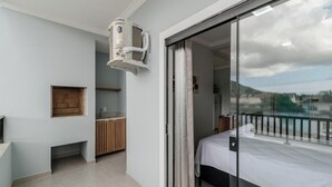 Habitación de hotel con cama, kitchenette pequeña, ventana con vista y ventilador de techo.