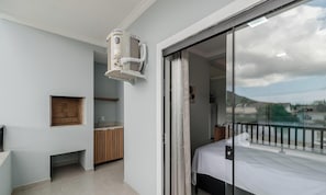 Ein modernes Schlafzimmer mit Bett, einer Schiebeglastür zum Balkon, einer kleinen Küchenzeile und einer eingebauten Klimaanlage.