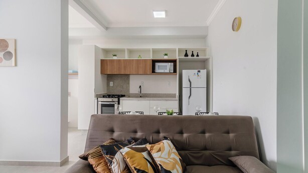 Una sala de estar moderna con un sofá marrón, una mesa de comedor con sillas y una cocina al fondo.
