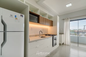 Een moderne keuken met een ingebouwde magnetron, gasfornuis en een roestvrijstalen spoelbak.
