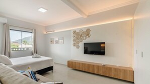 Une chambre d’hôtel moderne équipée d’un lit, d’un canapé, d’une télévision et d’un meuble de divertissement fixé au mur.