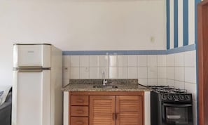 A compact kitchen with a refrigerator, a sink, wooden cabinets, and a stove. - Comfortable Apartment Beachfront Condo Jso0007 (Porto Seguro)
