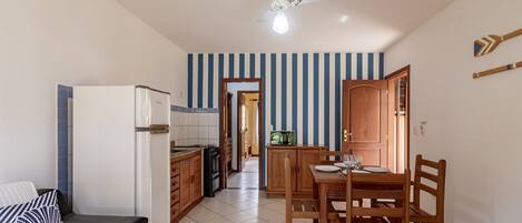 Cocina pequeña con refrigerador, microondas y armarios de madera.